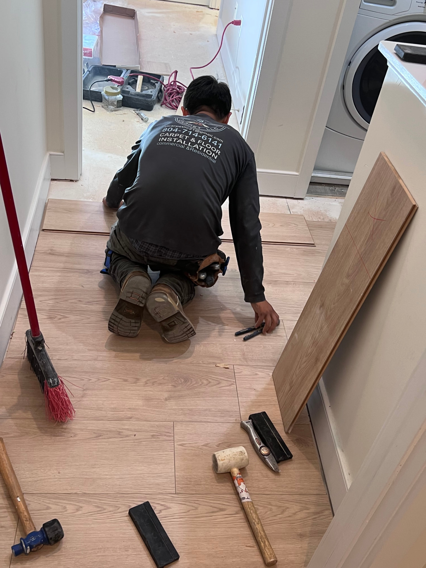 Installer fitting light oak LVP planks in a home hallway