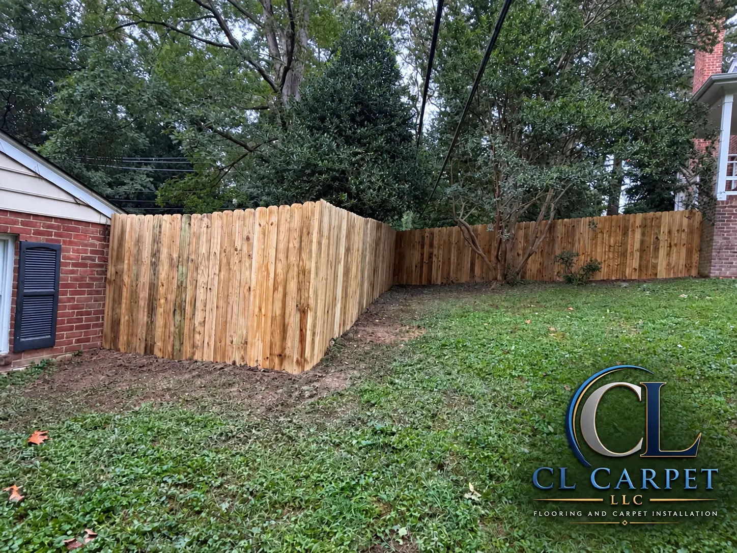 New wood privacy fence wrapping a brick home's backyard