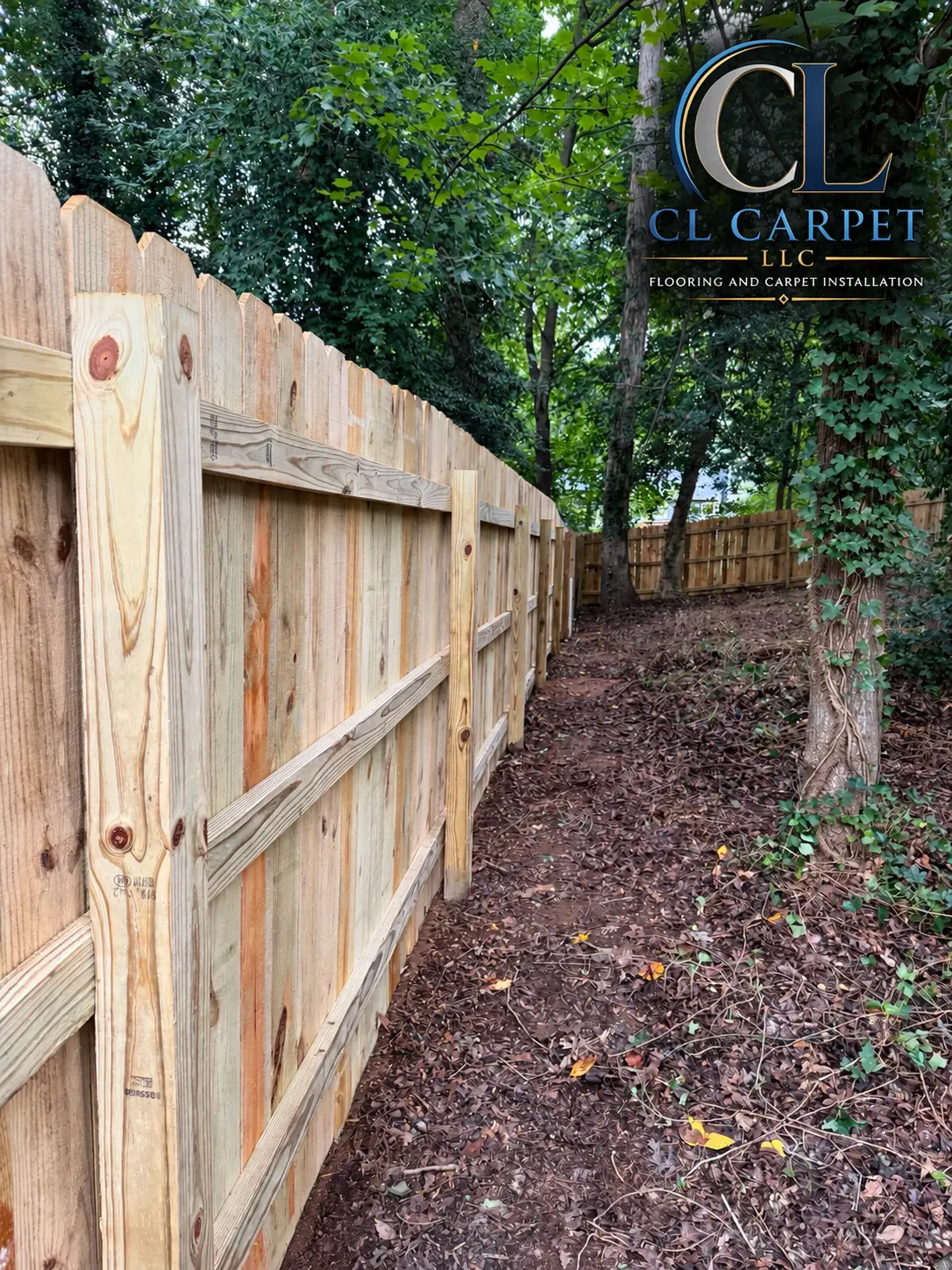 New wood privacy fence installed along a tree line